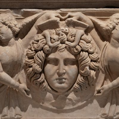 Close-up of a detailed bas relief sculpture featuring Medusa with angels in stone.